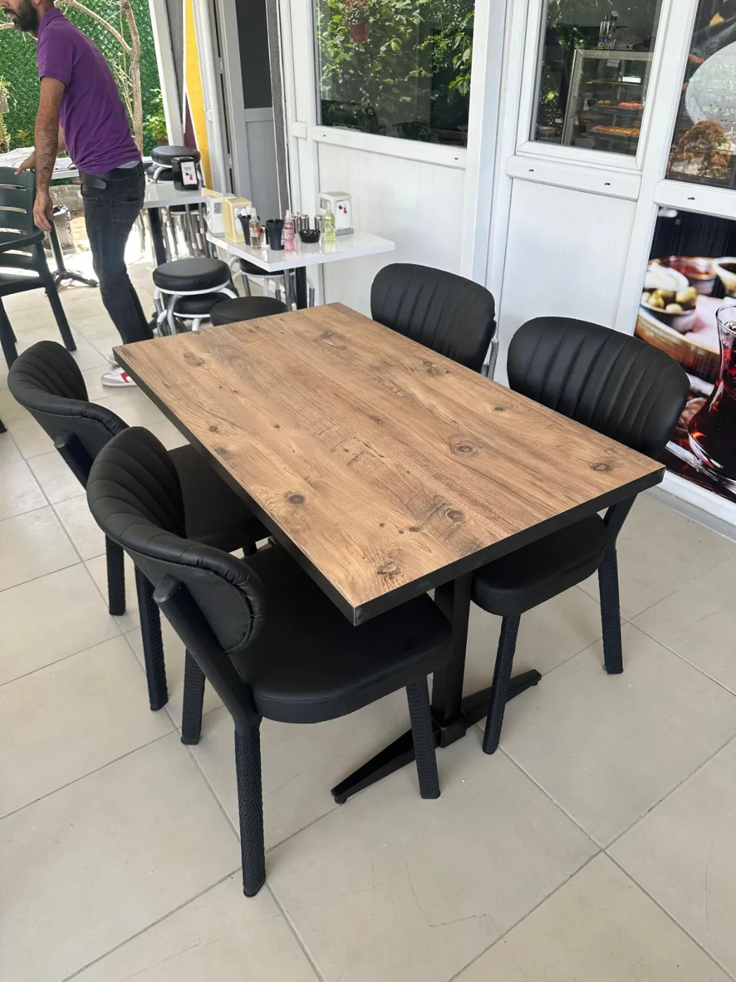 Ahşap desenli masa ve siyah sandalyelerden oluşan cafe düzeni